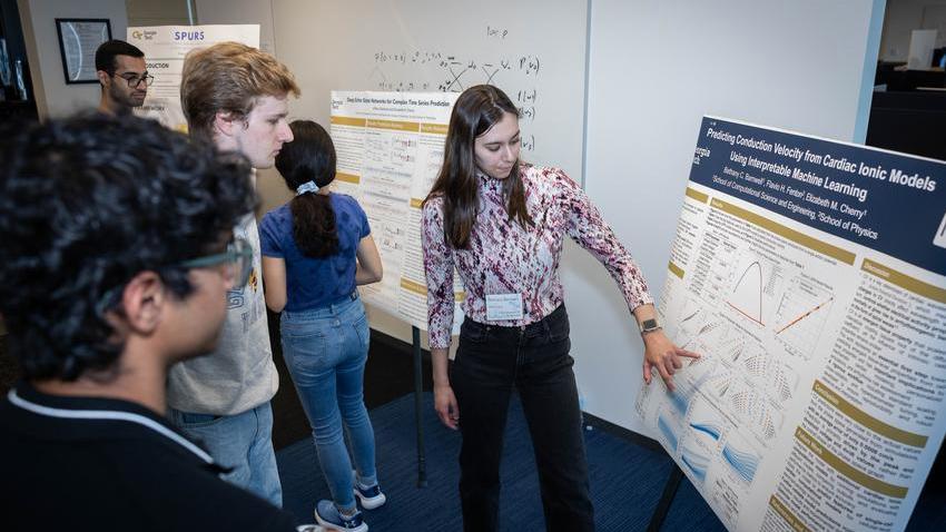 A graduate student presenting a poster to peers.